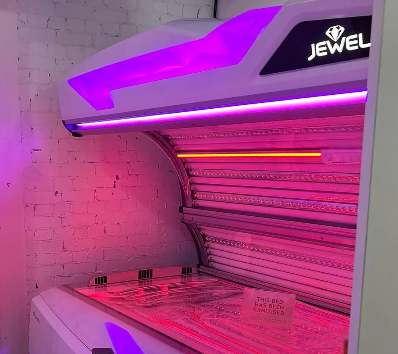 A Luxura Jewel installed against a white brick wall, its canopy open and lit pink and violet