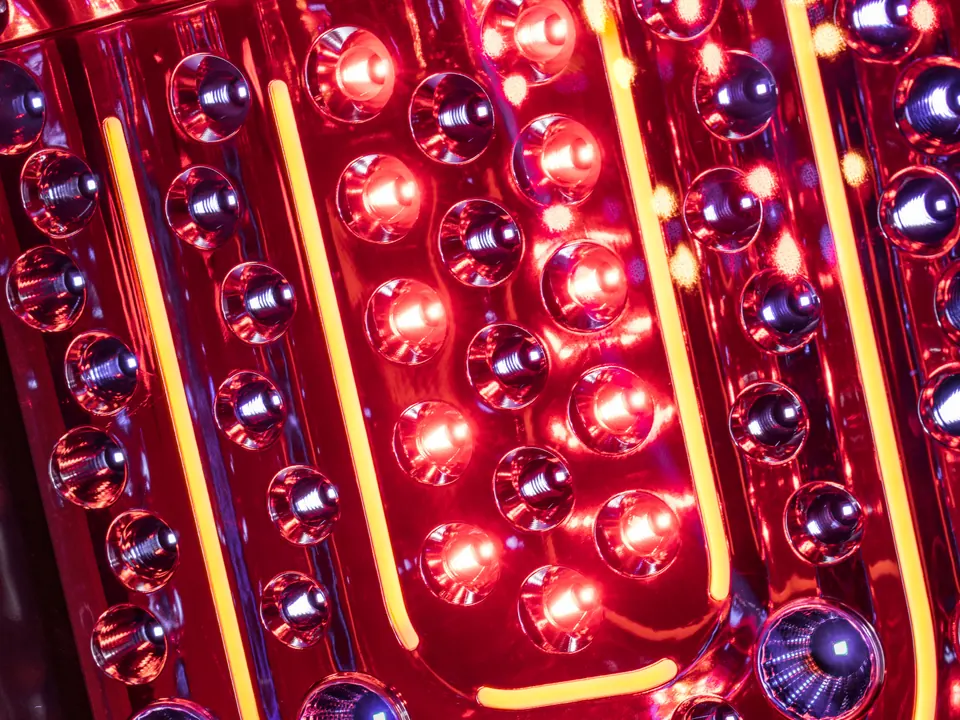 Close-up of the Jewel Elite's face tanner: LEDs in polished reflector cups, lit red, between amber light strips