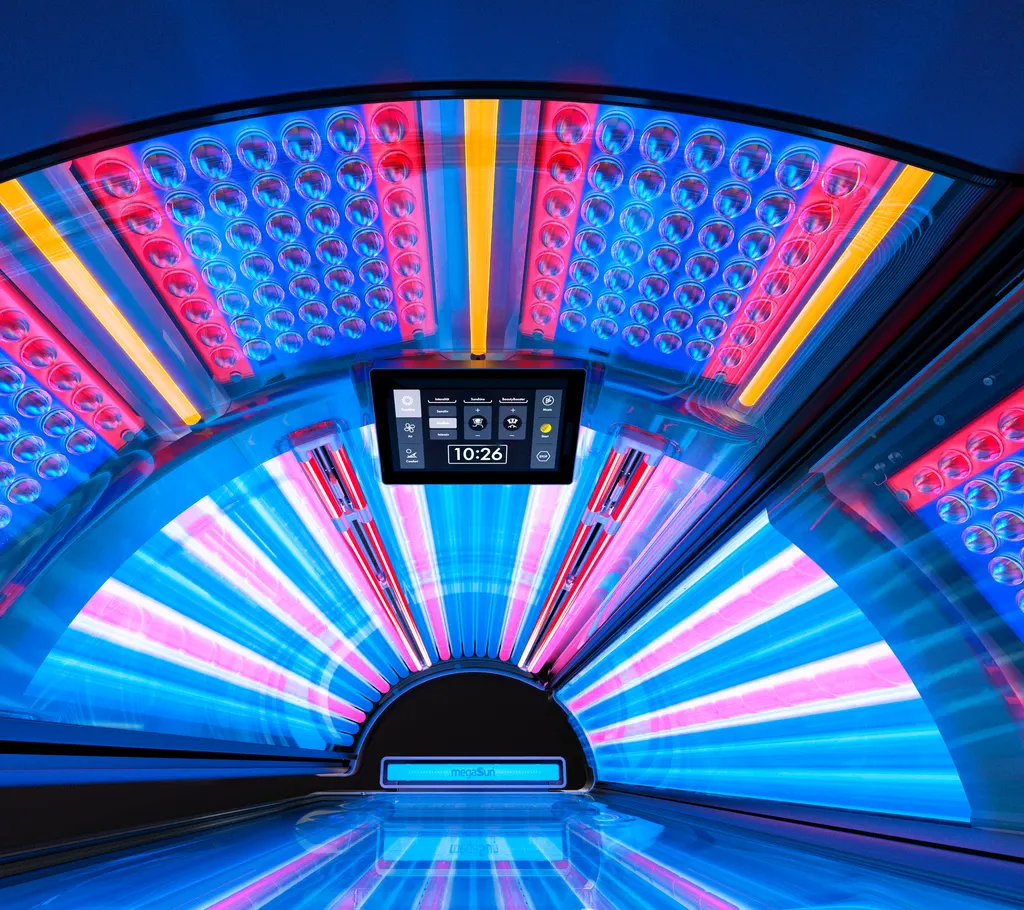 Looking up into an open K-Series canopy: tubes fanning out, LED facial panels with yellow UV-B lamps, and the touch display in the middle